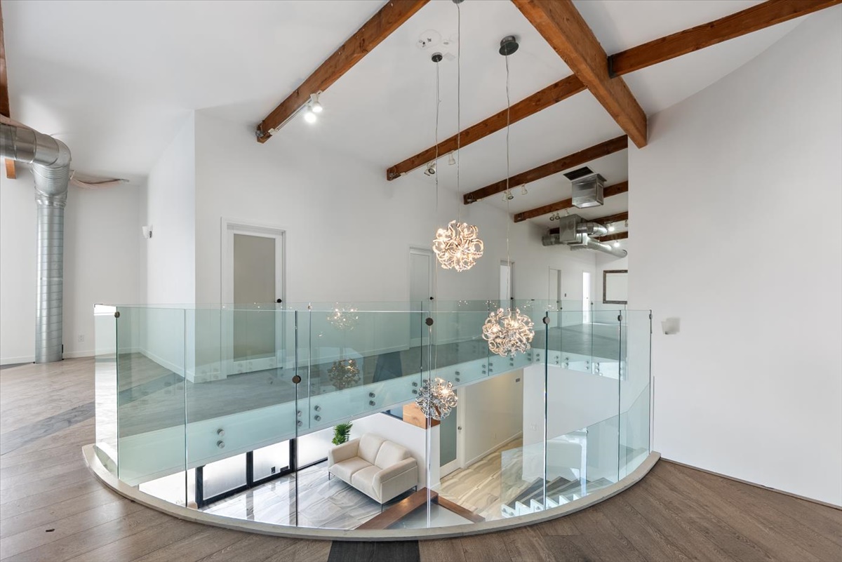 Upstairs mezzanine workspace with glass rail and chandelier